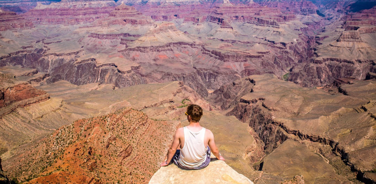 man sitting on ledge at Grand Canyon