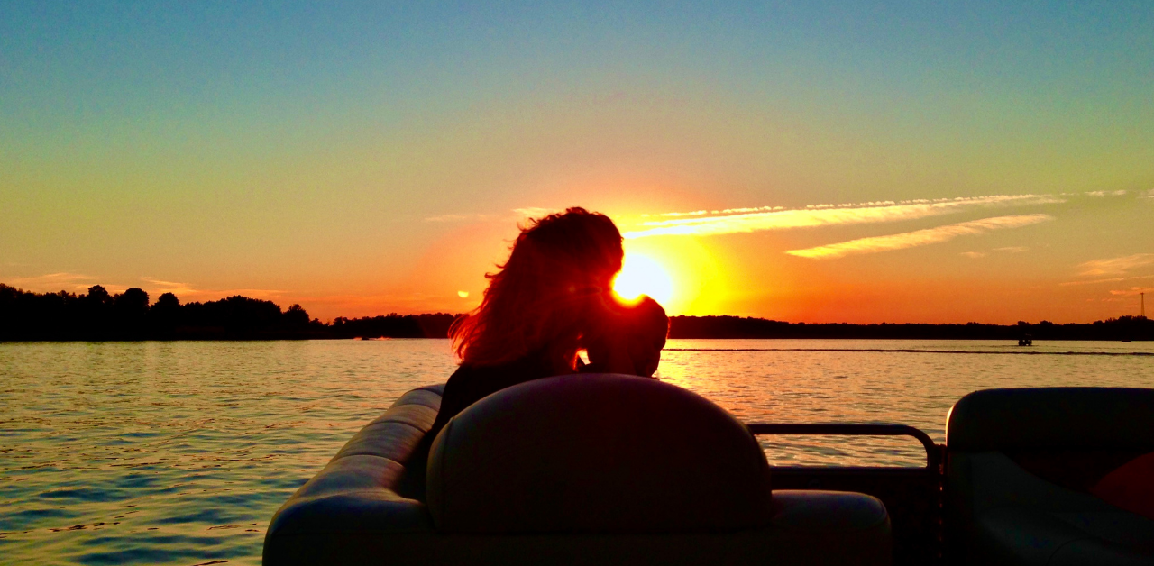 mom and child on pontoon boat on lake at sunset