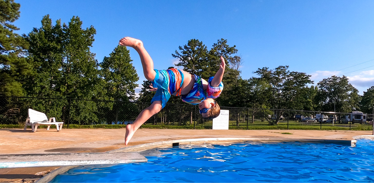 boy doing somersault from pool diving board